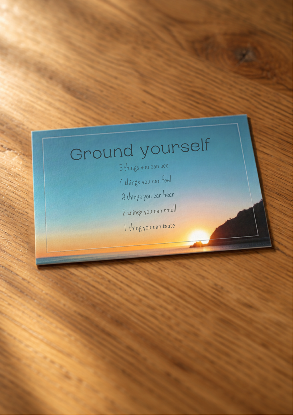 Grounding and square breathing cards with sunset designs displayed on a wooden surface.